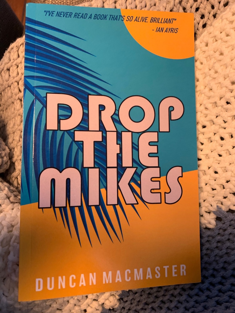 Paperback copy of Drop the Mikes